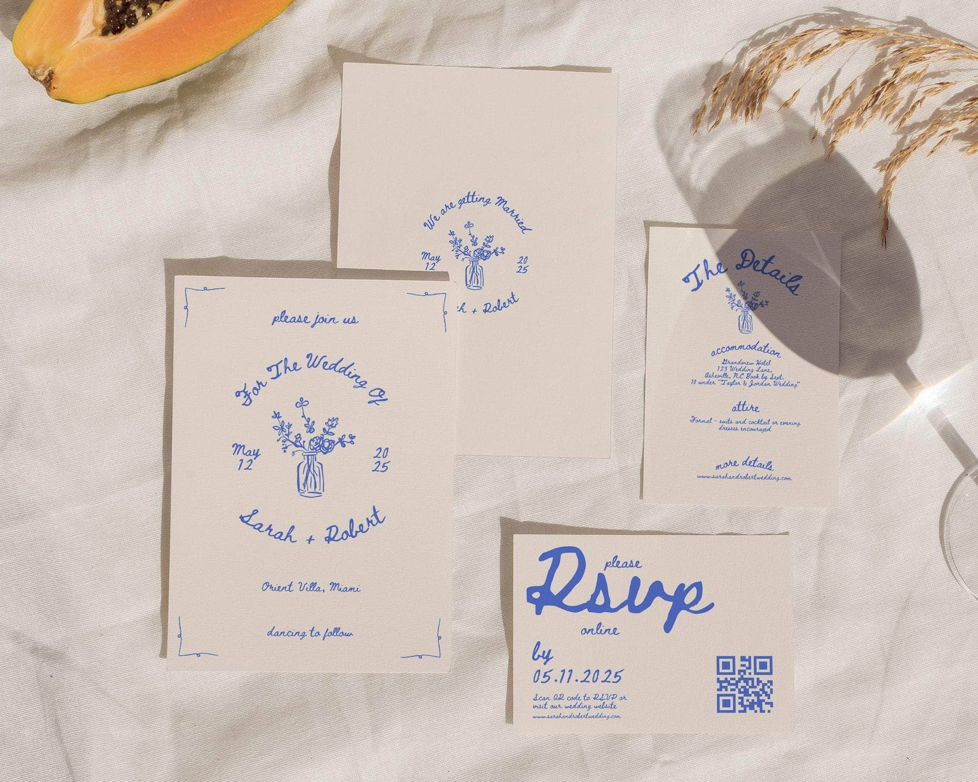 Wedding invitation set with blue text on beige paper, featuring a papaya and dried flowers.